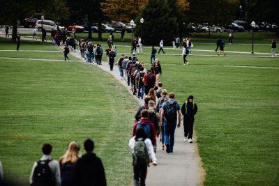 A sidewalk crossing the Drillfield is filled with students,